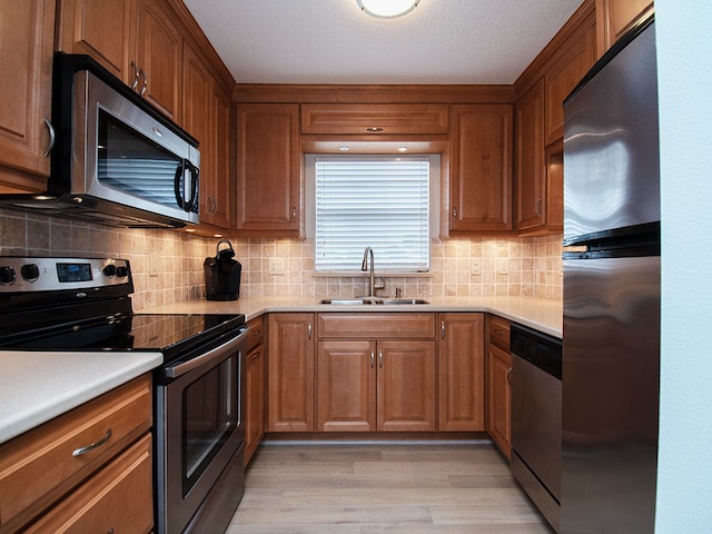 kitchen featuring stainless steel appliances, a sink, and brown cabinets