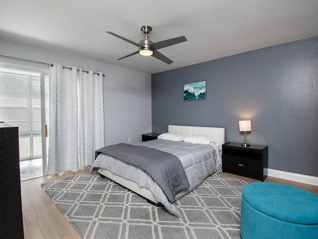 bedroom with a textured ceiling, ceiling fan, wood finished floors, and baseboards