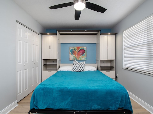 bedroom with light wood finished floors, baseboards, and a ceiling fan