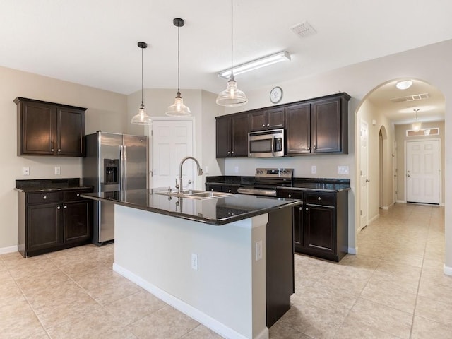 kitchen with visible vents, a sink, dark countertops, stainless steel appliances, and arched walkways