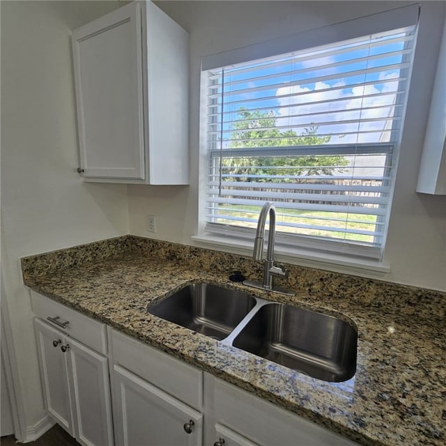 kitchen featuring white cabinets, sink, and stone counters