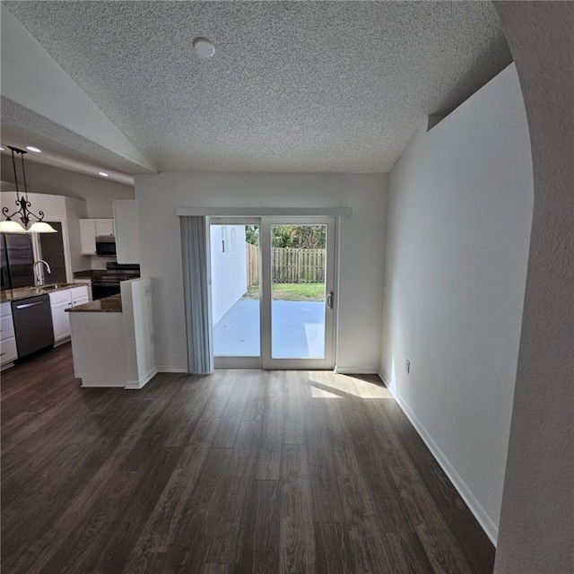 unfurnished living room featuring a textured ceiling, sink, dark hardwood / wood-style floors, and vaulted ceiling