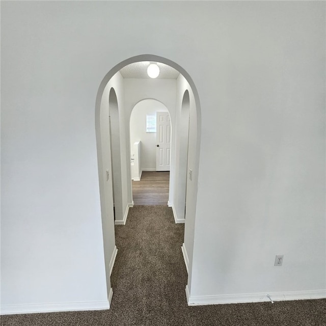 hallway featuring dark colored carpet