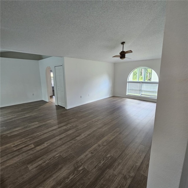 unfurnished living room featuring dark hardwood / wood-style floors, ceiling fan, and a textured ceiling