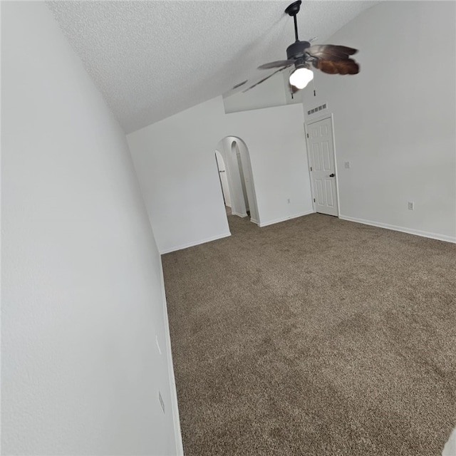 carpeted spare room with a textured ceiling, vaulted ceiling, and ceiling fan