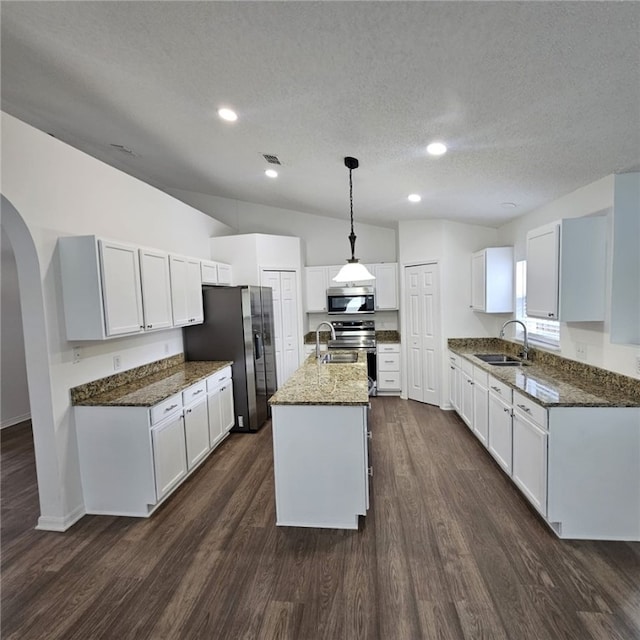 kitchen with white cabinetry, dark hardwood / wood-style flooring, pendant lighting, a kitchen island with sink, and appliances with stainless steel finishes