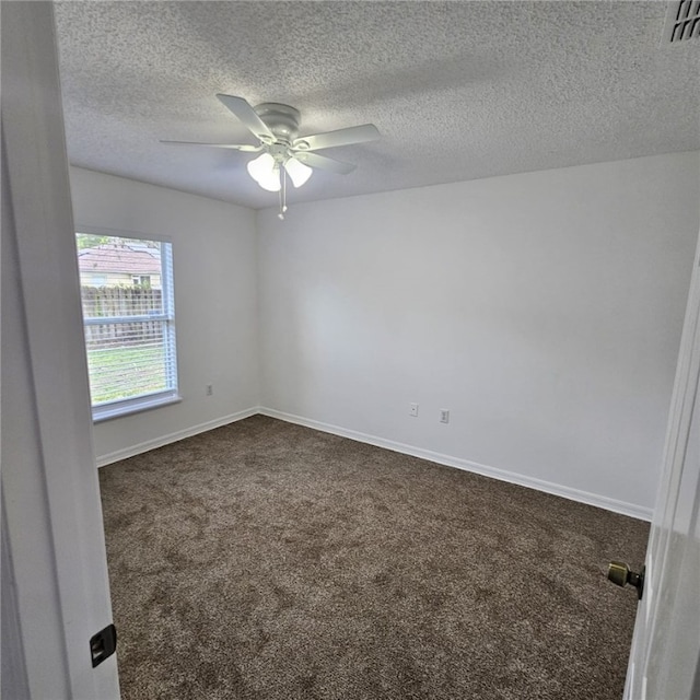 empty room with a textured ceiling, dark carpet, and ceiling fan