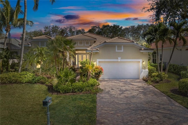 mediterranean / spanish house with a garage and a lawn