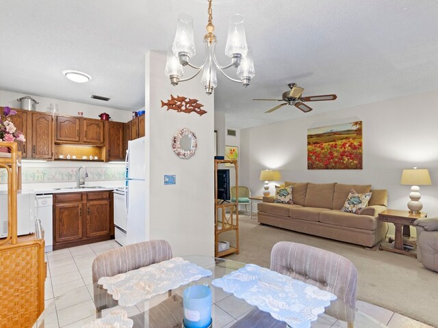 tiled dining room featuring a textured ceiling, sink, and ceiling fan with notable chandelier