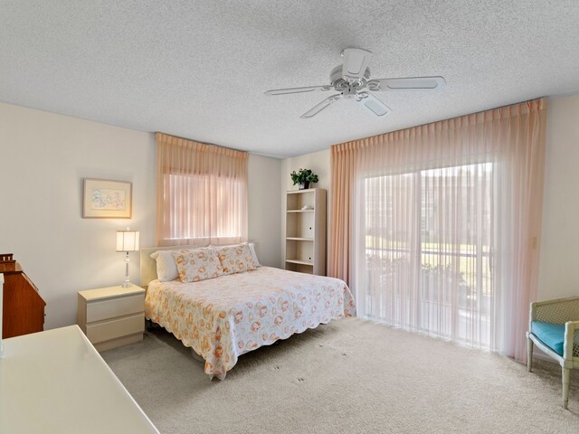 bedroom featuring ceiling fan, multiple windows, a textured ceiling, and carpet floors