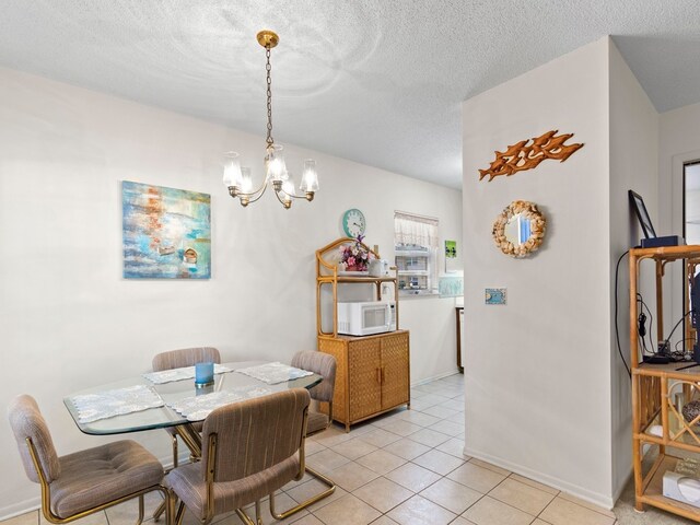 tiled dining room featuring a textured ceiling and a notable chandelier