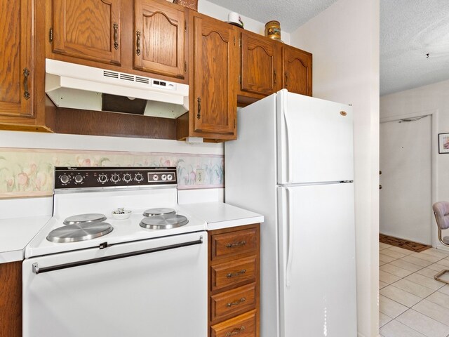 kitchen featuring white appliances, a textured ceiling, and light tile patterned floors