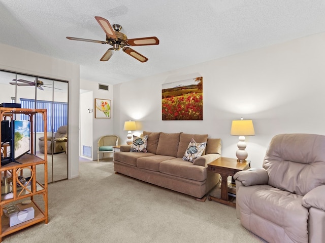 living room featuring a textured ceiling, light colored carpet, and ceiling fan