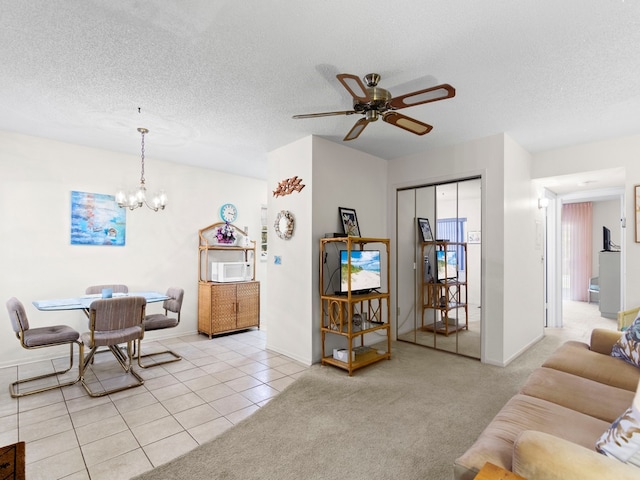 living room with a textured ceiling, ceiling fan with notable chandelier, and light carpet