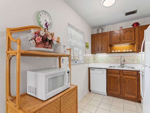 kitchen with white appliances, a textured ceiling, sink, and light tile patterned flooring