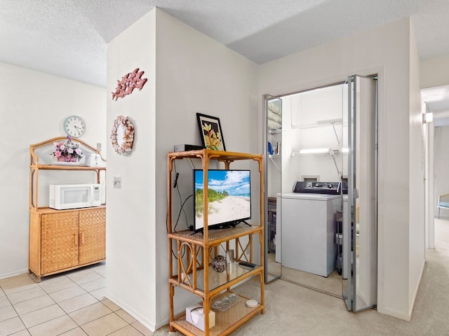 hallway featuring separate washer and dryer, light carpet, and a textured ceiling