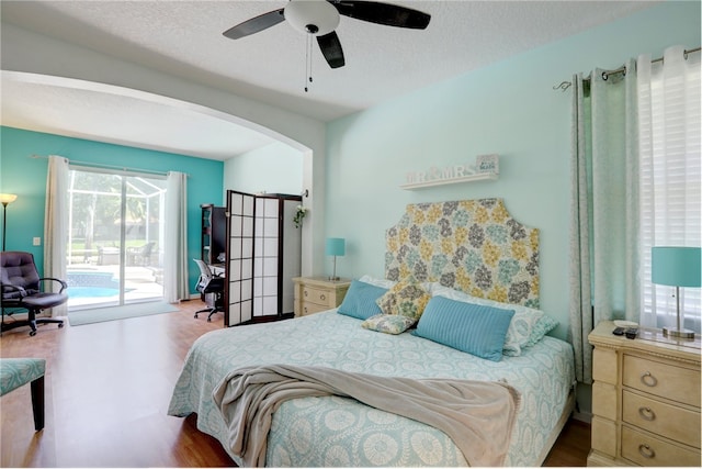 bedroom featuring ceiling fan, hardwood / wood-style flooring, access to exterior, and a textured ceiling