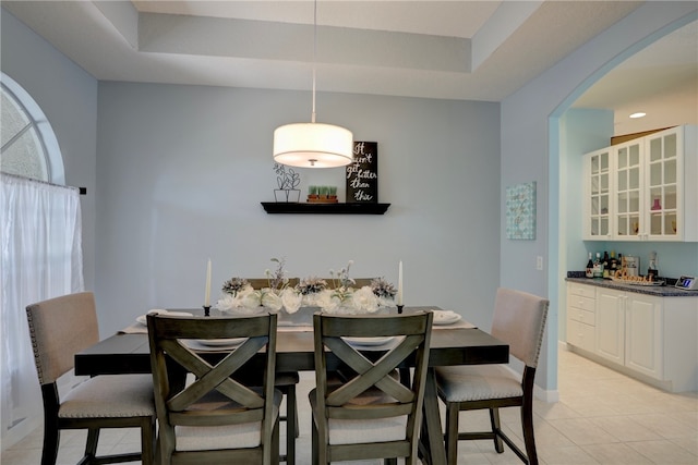 dining space featuring light tile patterned floors and a raised ceiling