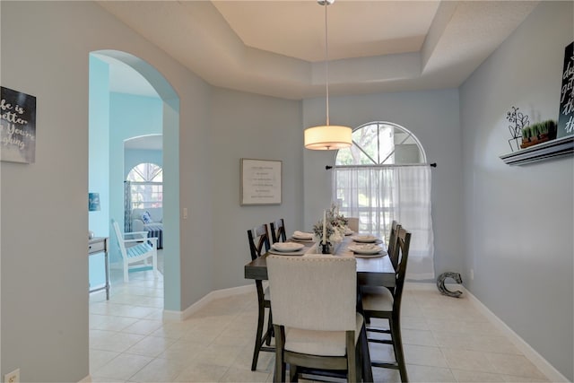 tiled dining area featuring a tray ceiling