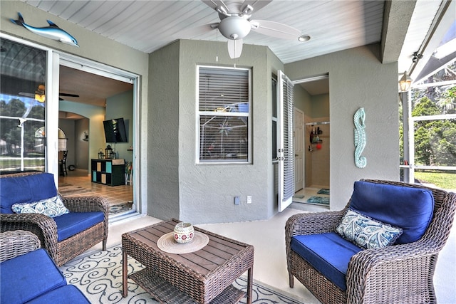 view of patio with ceiling fan, glass enclosure, and an outdoor living space