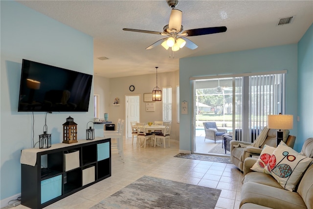 living room with a textured ceiling, light tile patterned flooring, and ceiling fan with notable chandelier