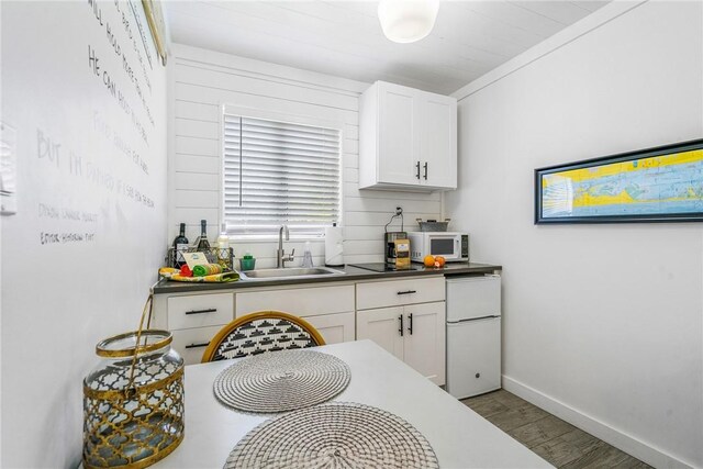 kitchen featuring white cabinets, hardwood / wood-style floors, white appliances, and sink