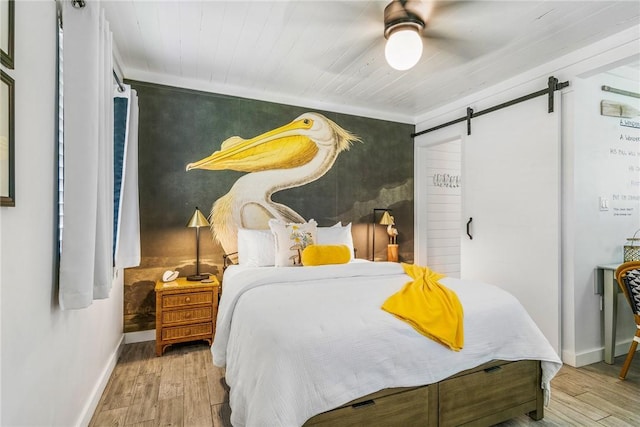 bedroom with crown molding, light hardwood / wood-style flooring, ceiling fan, a barn door, and wood ceiling