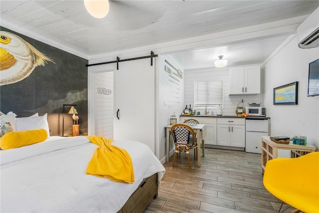 bedroom with a wall unit AC, crown molding, a barn door, white refrigerator, and hardwood / wood-style floors