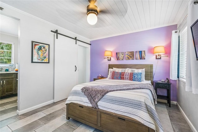 bedroom featuring wooden ceiling, ensuite bath, ceiling fan, a barn door, and ornamental molding