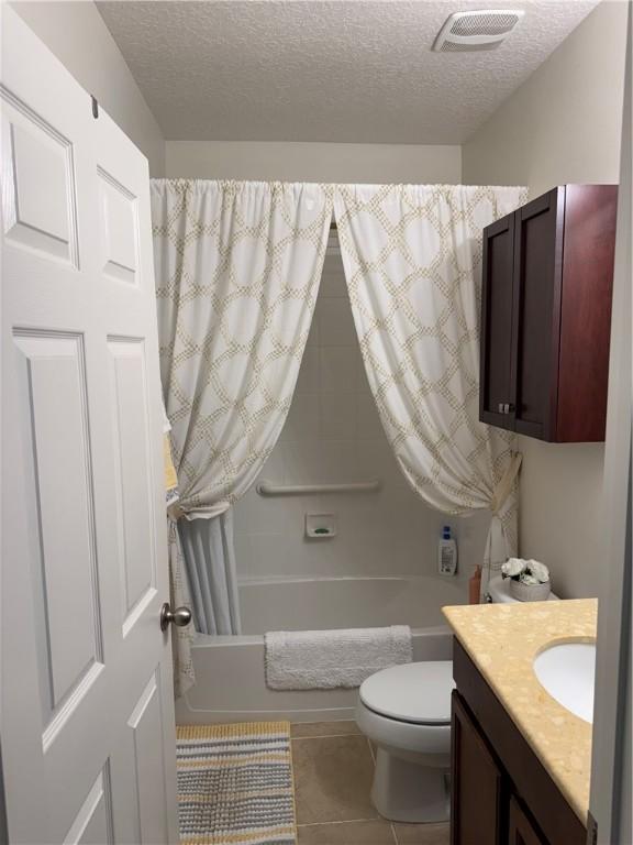 full bathroom featuring a textured ceiling, tile patterned floors, shower / bath combo, and vanity