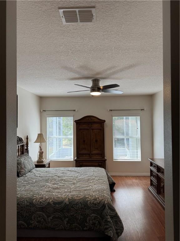 bedroom featuring ceiling fan, hardwood / wood-style floors, and a textured ceiling