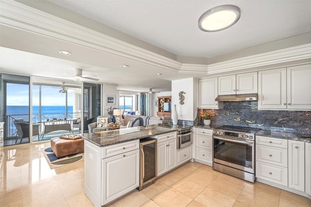 kitchen with backsplash, a water view, appliances with stainless steel finishes, kitchen peninsula, and beverage cooler