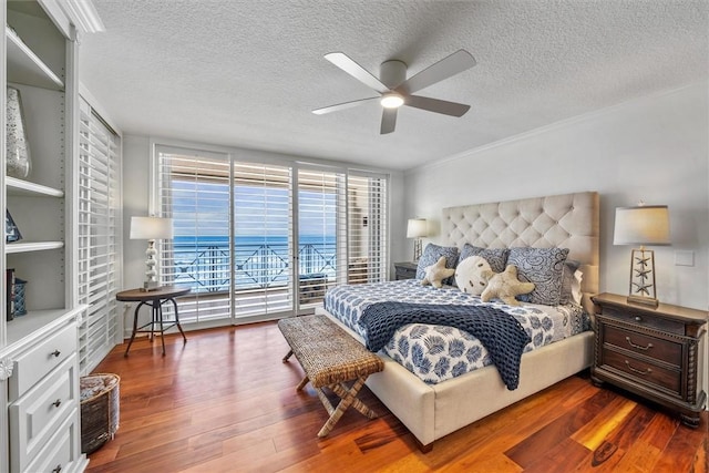 bedroom featuring a textured ceiling, ceiling fan, access to exterior, and dark wood-type flooring