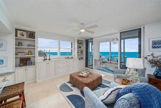 living room featuring a water view, crown molding, ceiling fan, built in features, and a textured ceiling