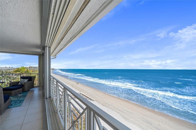 balcony with a water view and a view of the beach