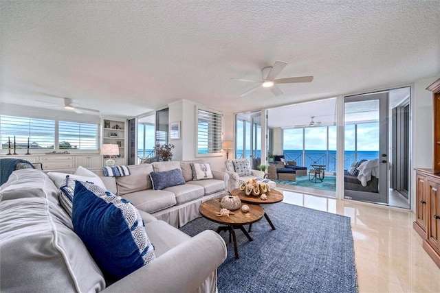 living room featuring ceiling fan, built in features, a water view, and a textured ceiling