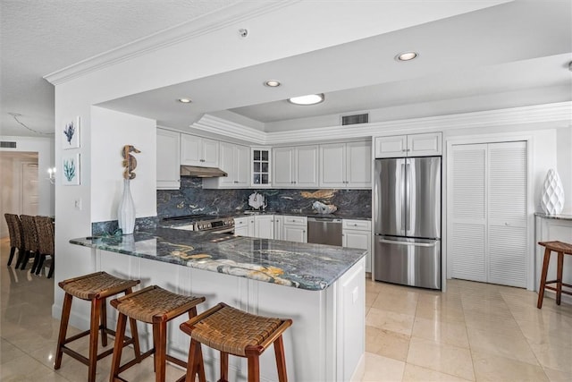 kitchen featuring kitchen peninsula, appliances with stainless steel finishes, tasteful backsplash, light tile patterned flooring, and white cabinetry