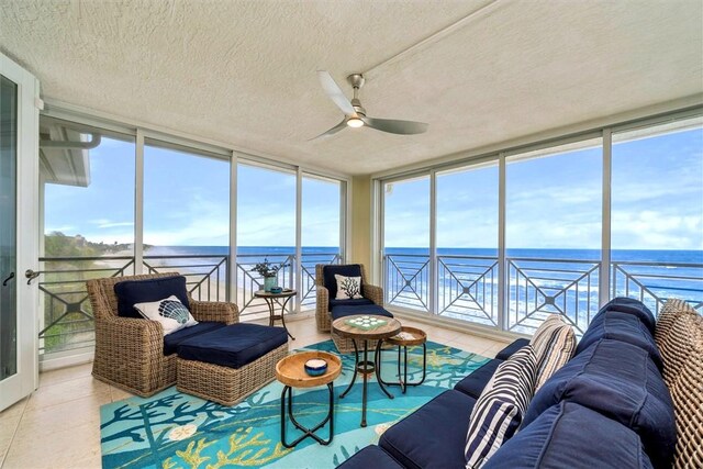 sunroom / solarium featuring ceiling fan, a water view, and a healthy amount of sunlight