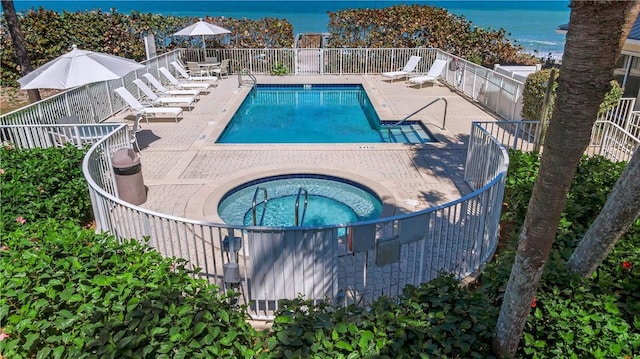 view of swimming pool with a patio, a water view, and a hot tub