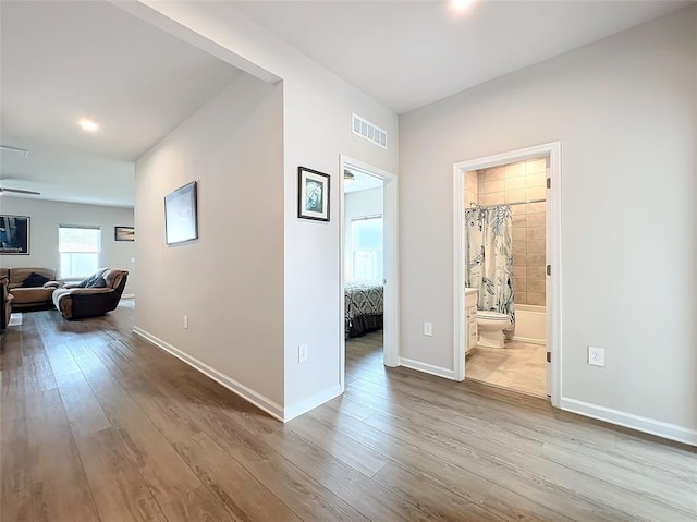 corridor with wood finished floors, visible vents, and baseboards