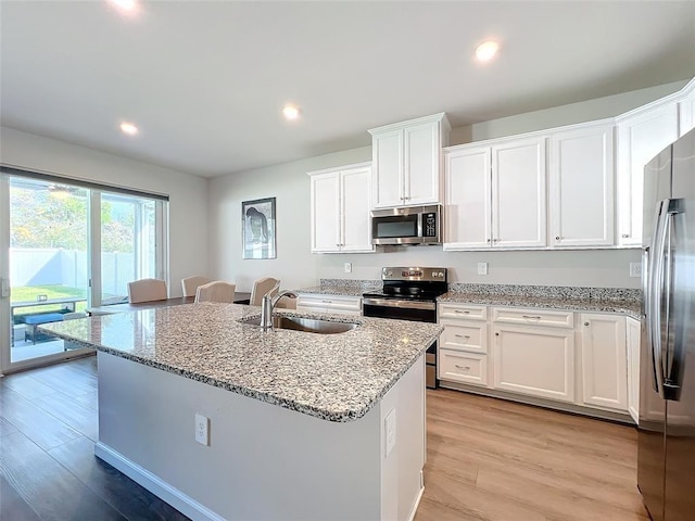 kitchen with light wood-style flooring, white cabinetry, stainless steel appliances, and a sink