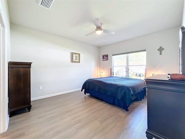 bedroom with ceiling fan, light wood-type flooring, visible vents, and baseboards