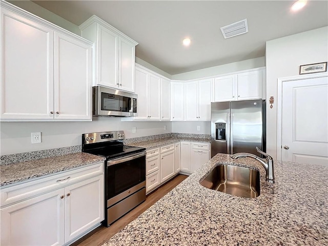 kitchen featuring stainless steel appliances, white cabinets, visible vents, and a sink