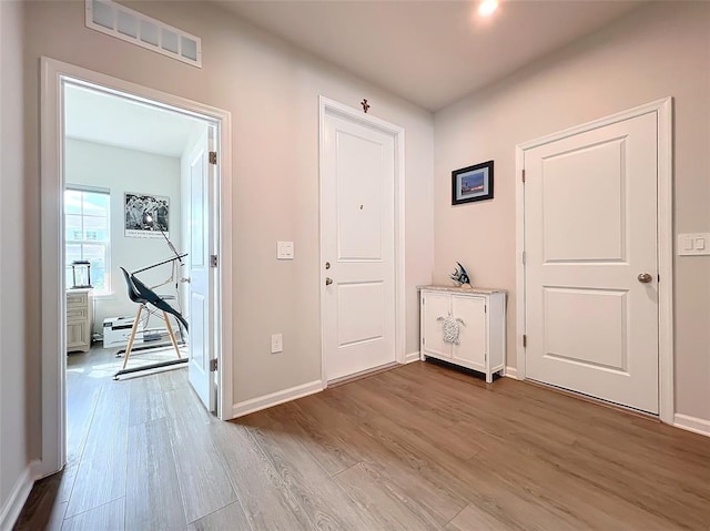 foyer with wood finished floors, visible vents, and baseboards