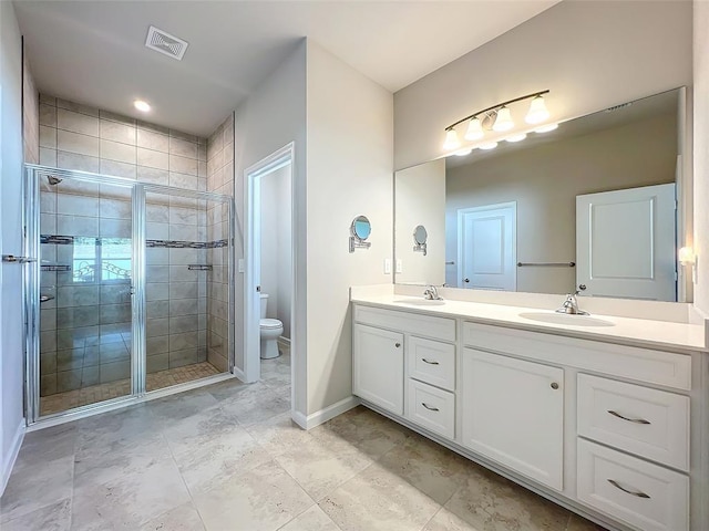 bathroom with toilet, a shower stall, double vanity, and a sink