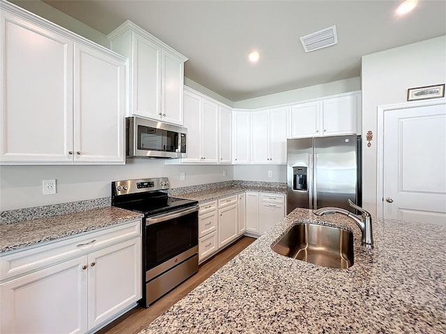 kitchen featuring stainless steel appliances, a sink, visible vents, and white cabinetry