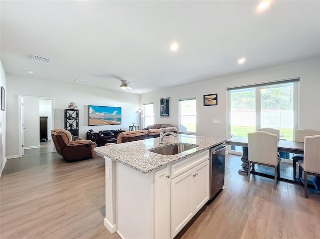 kitchen featuring dishwasher, visible vents, light wood finished floors, and a sink