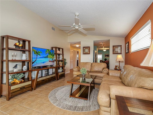 living room with ceiling fan, vaulted ceiling, a textured ceiling, and light tile patterned floors