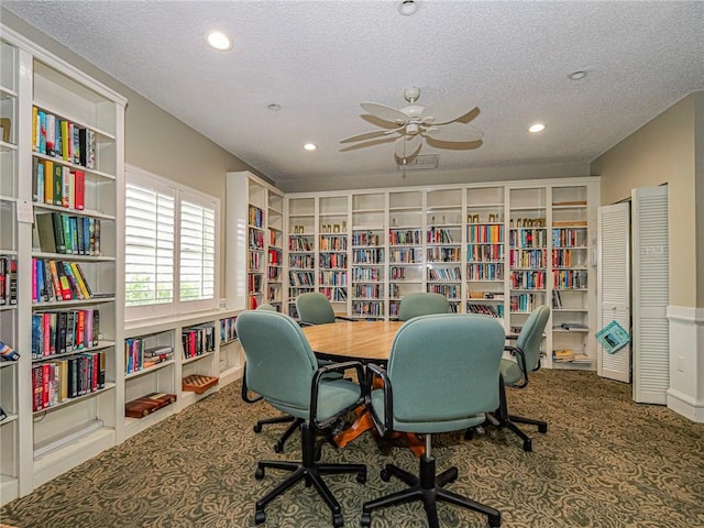 carpeted home office with ceiling fan and a textured ceiling