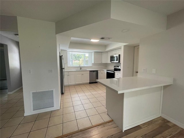 kitchen with appliances with stainless steel finishes, visible vents, a sink, and light tile patterned flooring